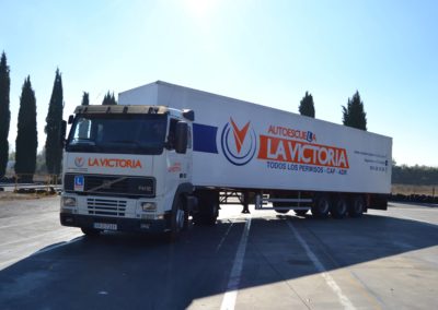 Imagen de un camión blanco de la autoescuela la victoria enganchado a un tráiler de carga