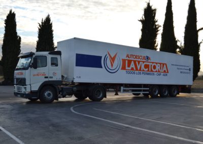 Imagen de un camión blanco de la autoescuela la victoria enganchado a un tráiler de carga