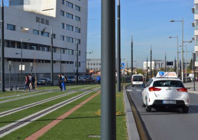 Imagen de un toyota auris blanco circulando en la vía pública cercano a una línea de tranvía